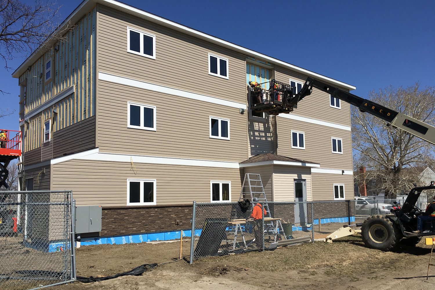 Construction workers installing siding on apartment building